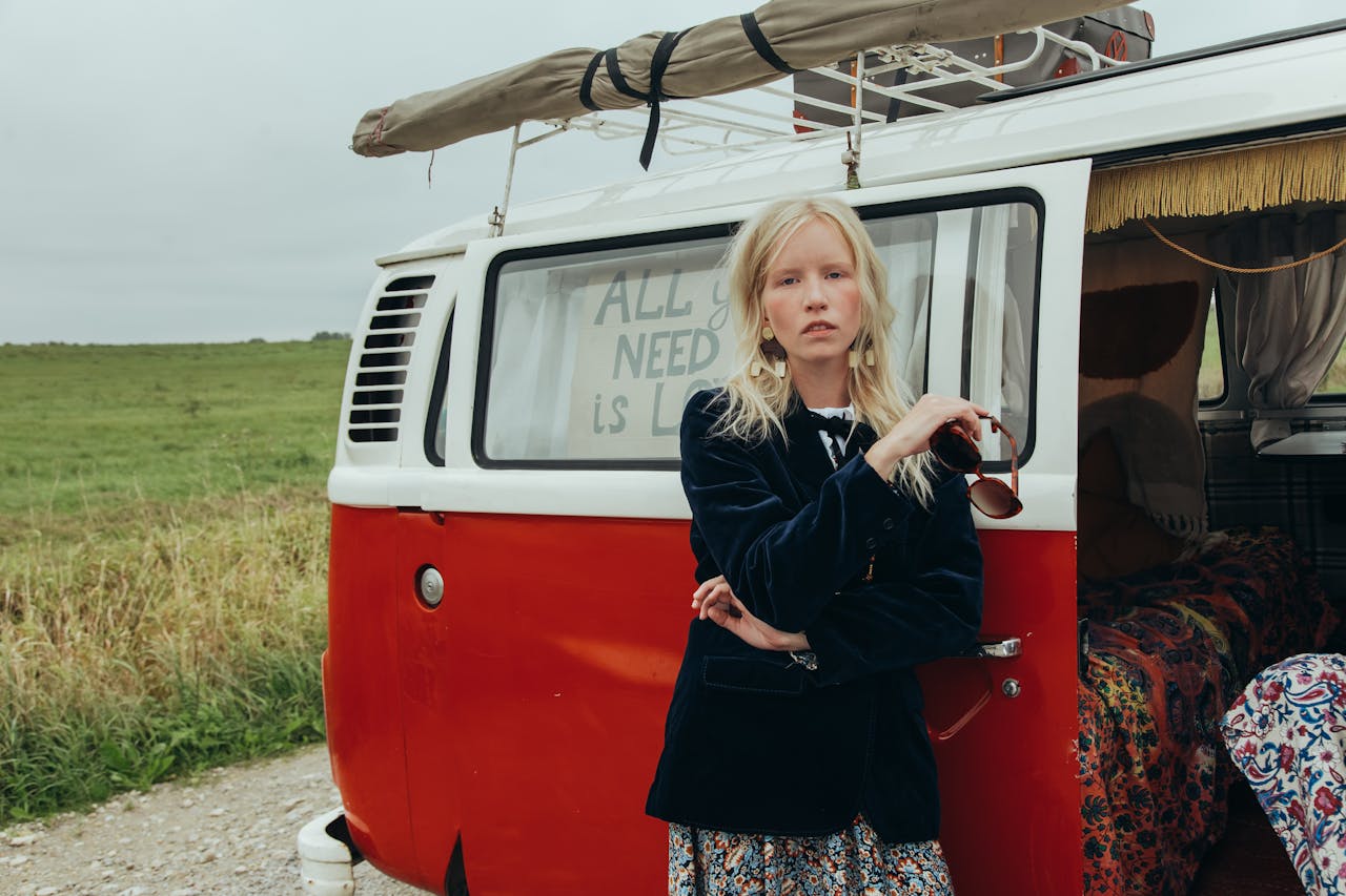 Woman in retro outfit stands by a vintage Volkswagen van, epitomizing a classic road trip vibe.